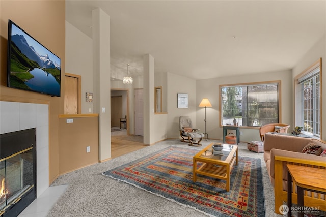 carpeted living area featuring an inviting chandelier, a fireplace, and vaulted ceiling