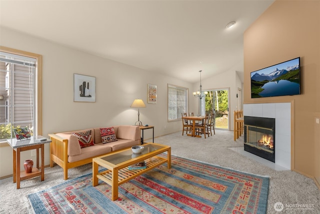 carpeted living room with a chandelier, a tile fireplace, and vaulted ceiling