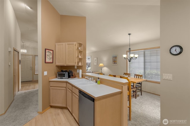 kitchen with light brown cabinets, a sink, a peninsula, dishwasher, and a chandelier