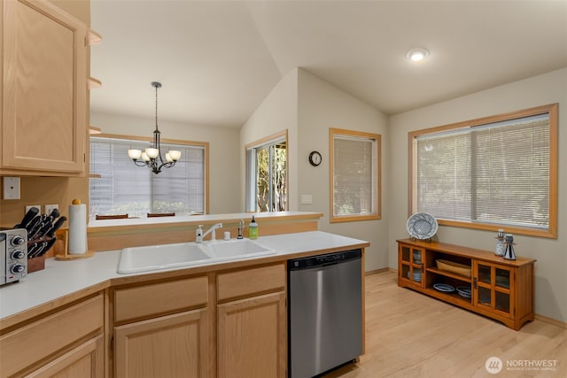 kitchen featuring light brown cabinets, a sink, stainless steel dishwasher, a peninsula, and lofted ceiling