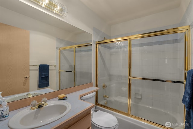 bathroom with vanity, toilet, and shower / bath combination with glass door