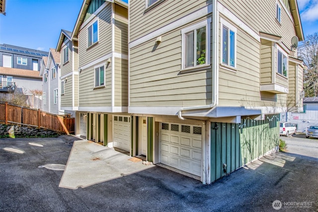 view of side of property featuring an attached garage and fence