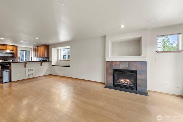 unfurnished living room featuring light wood finished floors, visible vents, and a tile fireplace