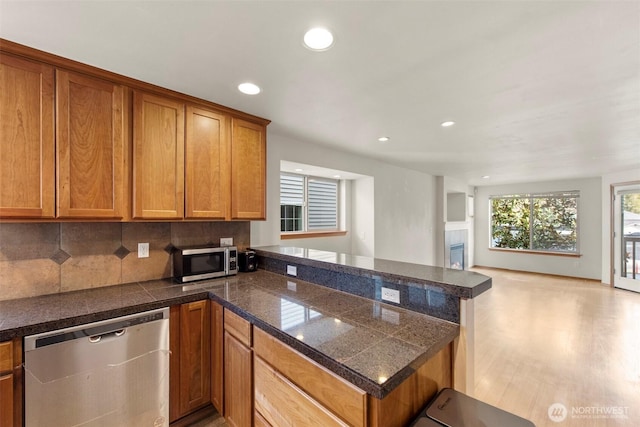 kitchen with brown cabinetry, tile countertops, a peninsula, and stainless steel appliances