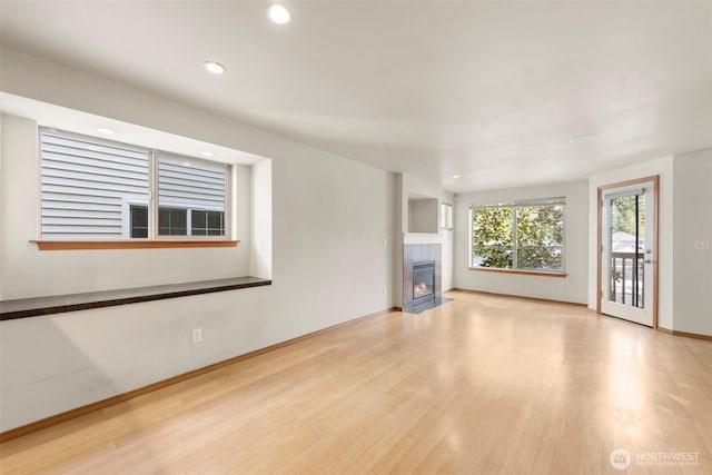 unfurnished living room with wood finished floors, recessed lighting, a fireplace, and baseboards