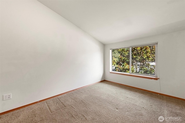 empty room featuring baseboards, lofted ceiling, and carpet floors