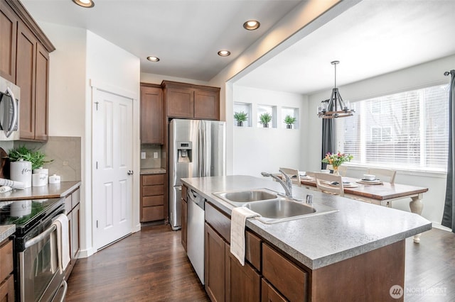 kitchen with an inviting chandelier, a sink, dark wood-type flooring, appliances with stainless steel finishes, and tasteful backsplash