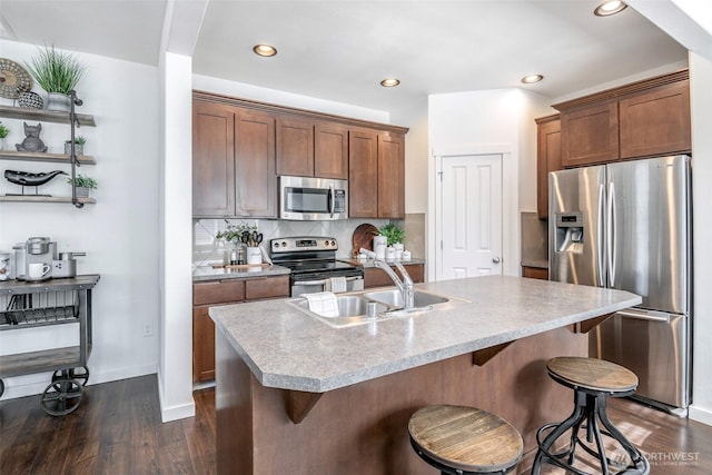 kitchen with a kitchen bar, backsplash, appliances with stainless steel finishes, and dark wood finished floors