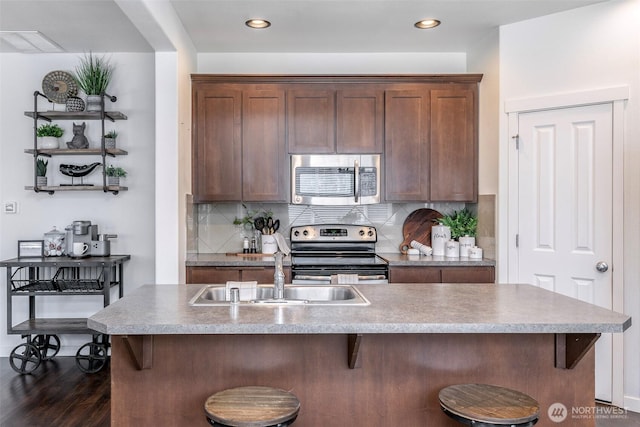 kitchen featuring backsplash, dark wood-type flooring, a breakfast bar, appliances with stainless steel finishes, and a sink