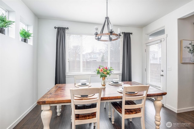 dining area featuring a chandelier, a healthy amount of sunlight, dark wood finished floors, and baseboards