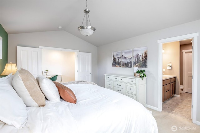 bedroom with light colored carpet, baseboards, ensuite bathroom, and lofted ceiling