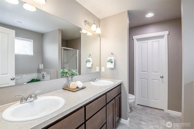 bathroom with a sink, toilet, a stall shower, and double vanity