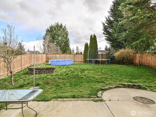 view of yard featuring a fenced backyard, a fenced in pool, a patio, and a trampoline