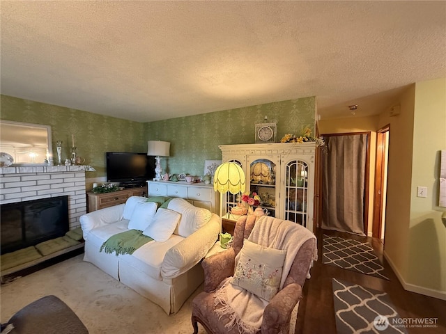 living area with wallpapered walls, a brick fireplace, baseboards, and a textured ceiling