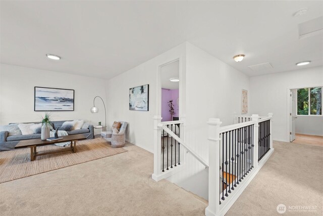 corridor with an upstairs landing, attic access, and carpet flooring