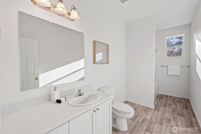 bathroom with toilet, wood finished floors, shower / tub combo, baseboards, and vanity