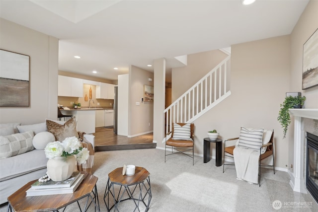 living area featuring a high end fireplace, baseboards, stairway, light colored carpet, and recessed lighting