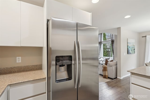 kitchen with wood finished floors, recessed lighting, stainless steel fridge, white cabinets, and light stone countertops