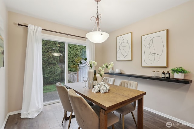 dining space featuring baseboards and wood finished floors