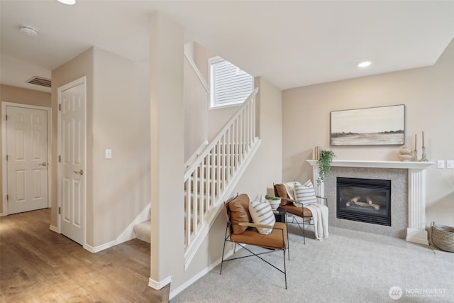 stairway featuring visible vents, baseboards, recessed lighting, wood finished floors, and a glass covered fireplace