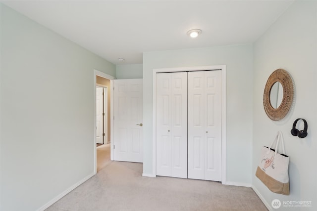 unfurnished bedroom featuring a closet, light colored carpet, and baseboards