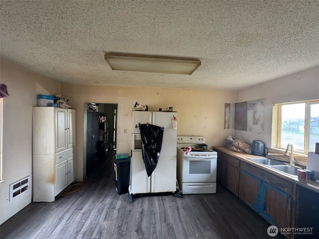 kitchen with white appliances, a sink, light countertops, dark wood-type flooring, and a textured ceiling