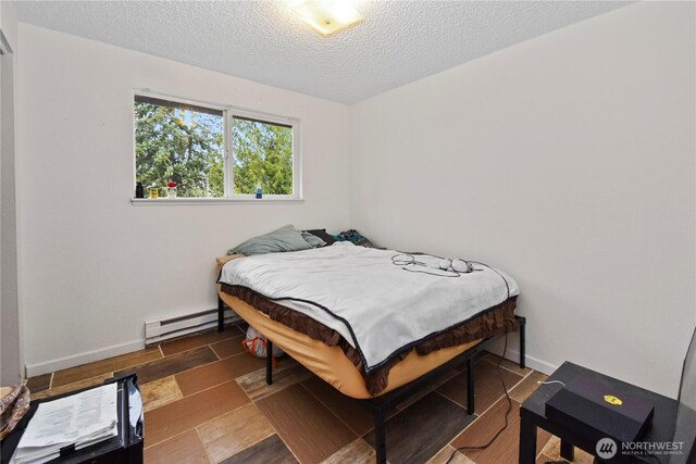 bedroom with baseboards, baseboard heating, wood finished floors, and a textured ceiling