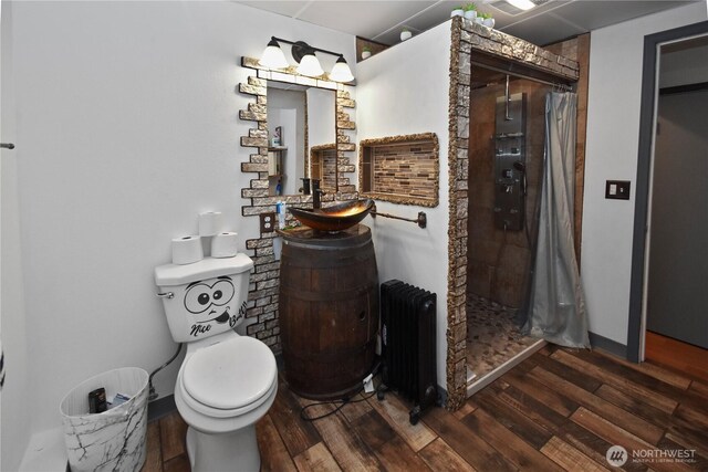 bathroom featuring a shower stall, radiator, and wood finished floors