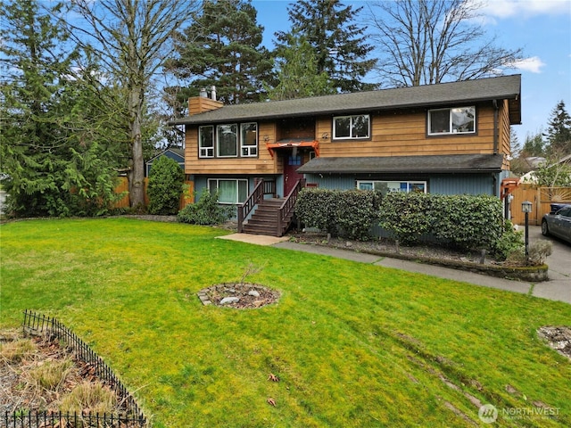 split foyer home with a front yard, a chimney, and fence