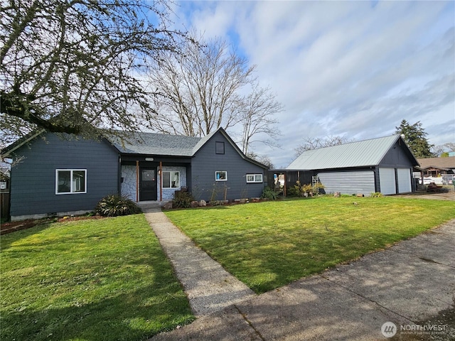 view of front of house with a detached garage, an outdoor structure, and a front yard