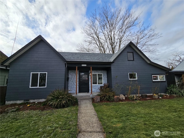 view of front of home featuring a porch, a front yard, stone siding, and a shingled roof