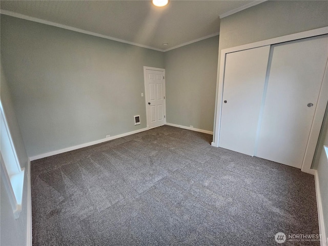 unfurnished bedroom featuring visible vents, baseboards, dark carpet, ornamental molding, and a closet