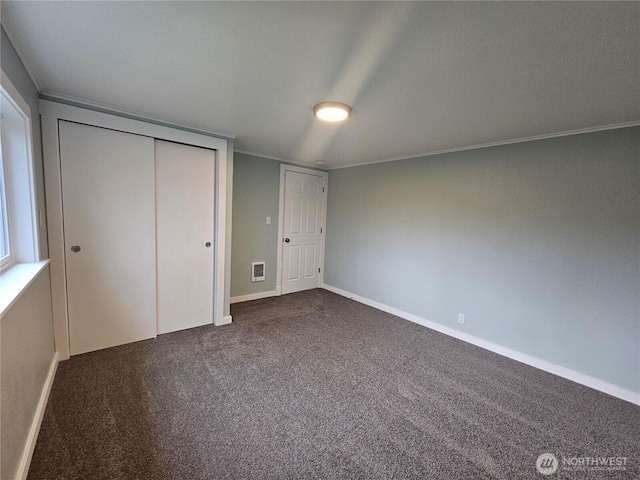 unfurnished bedroom featuring a closet, visible vents, baseboards, and dark colored carpet