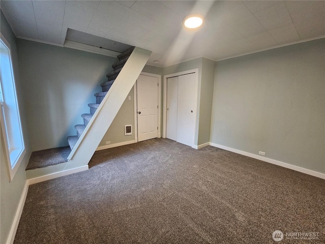 basement featuring stairway, baseboards, dark carpet, and ornamental molding