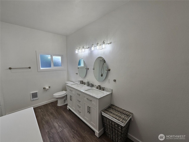 full bathroom featuring double vanity, toilet, wood finished floors, and a sink