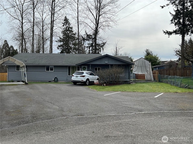 view of front of home with roof with shingles, a front lawn, and fence