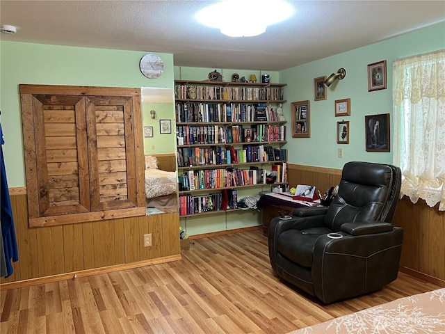 sitting room with wood finished floors, wood walls, and wainscoting