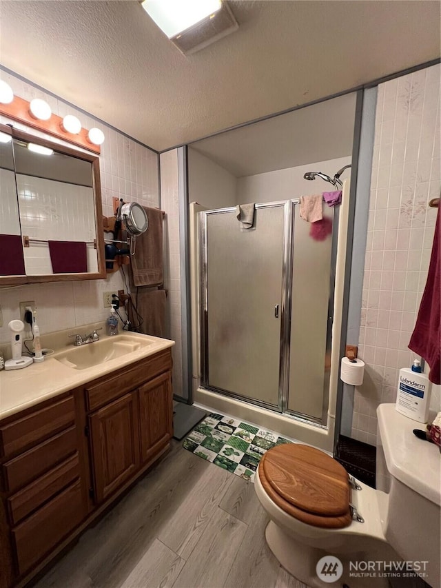 full bathroom featuring a shower stall, toilet, wood finished floors, and a textured ceiling