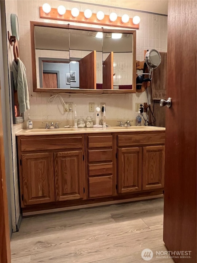 bathroom featuring decorative backsplash, double vanity, wood finished floors, and a sink