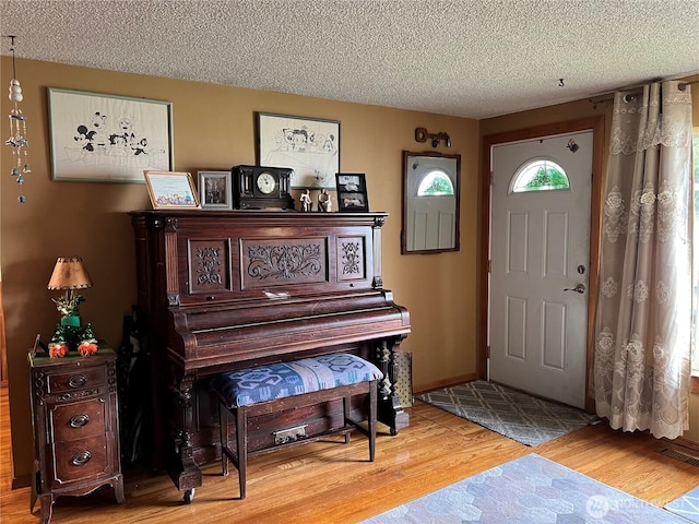 entrance foyer featuring visible vents, a textured ceiling, baseboards, and wood finished floors