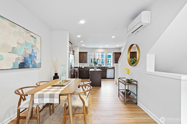 dining area with recessed lighting, light wood-type flooring, a wall mounted AC, and baseboards