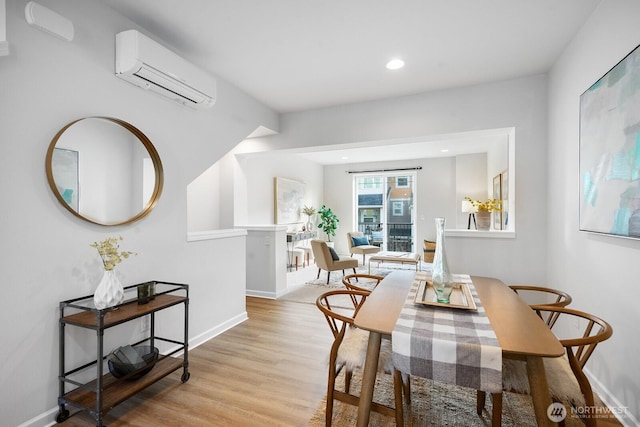 dining room with a wall unit AC, recessed lighting, baseboards, and light wood-type flooring