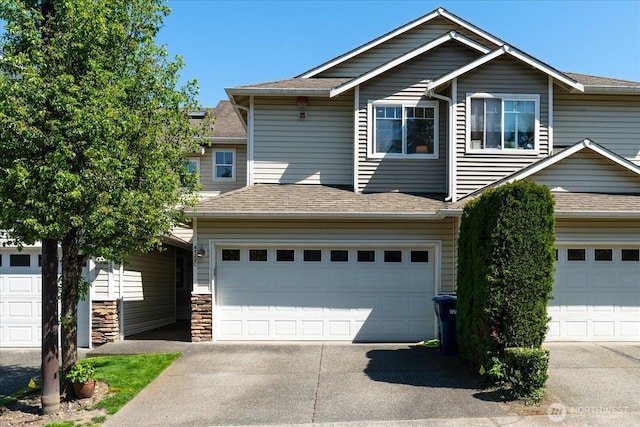 view of front facade with an attached garage, a shingled roof, driveway, and stone siding