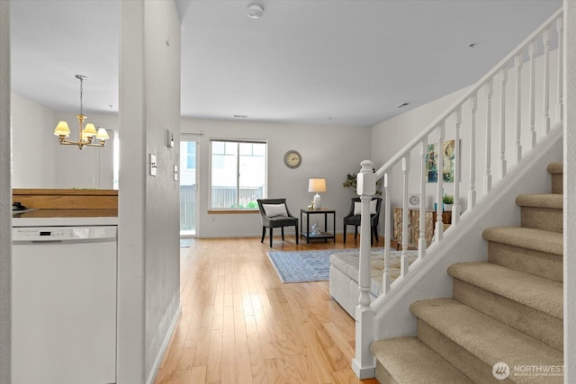 entryway with baseboards, a chandelier, stairway, and light wood-style floors