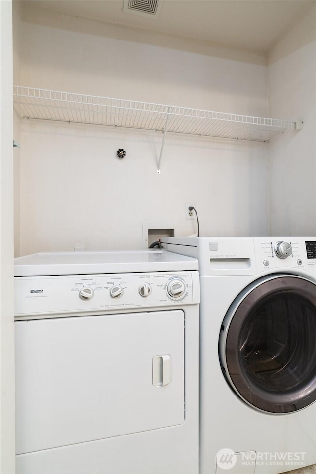 washroom featuring visible vents, laundry area, and washer and clothes dryer
