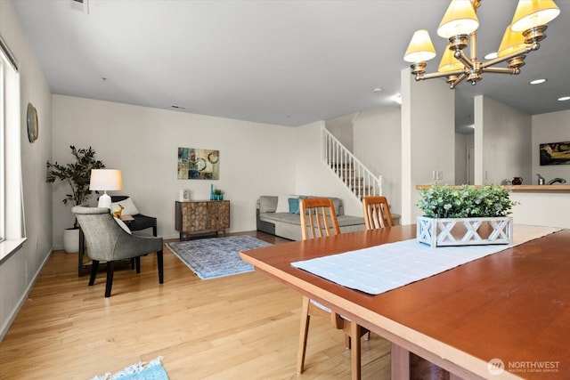 dining space featuring light wood-type flooring, recessed lighting, stairway, and an inviting chandelier