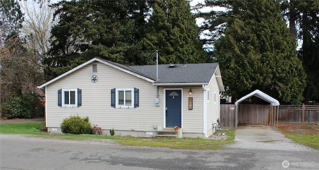 view of front facade with fence, driveway, a shingled roof, entry steps, and a carport