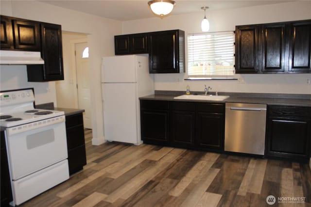 kitchen featuring under cabinet range hood, white appliances, dark wood finished floors, and a sink