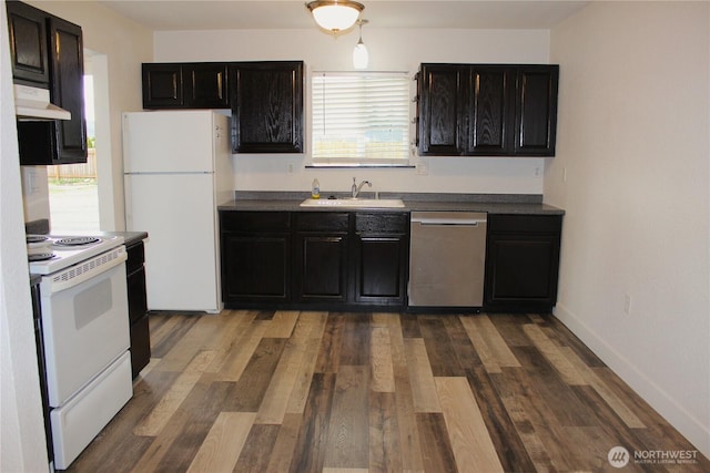 kitchen with under cabinet range hood, white appliances, dark cabinetry, and a sink