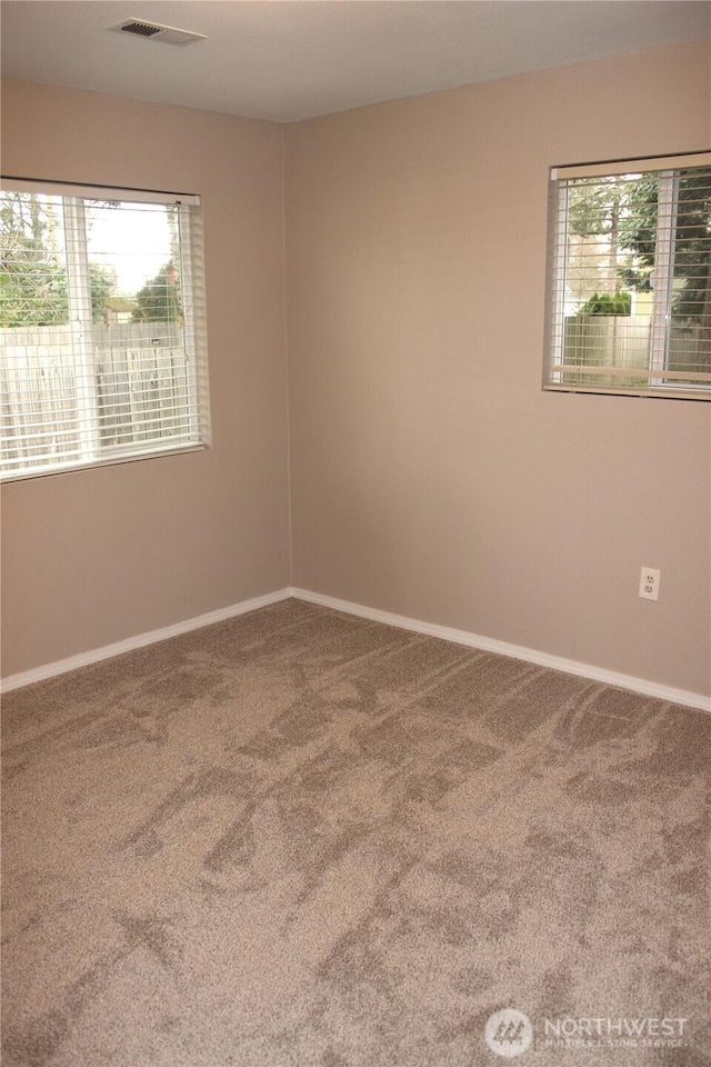 carpeted empty room featuring baseboards and visible vents